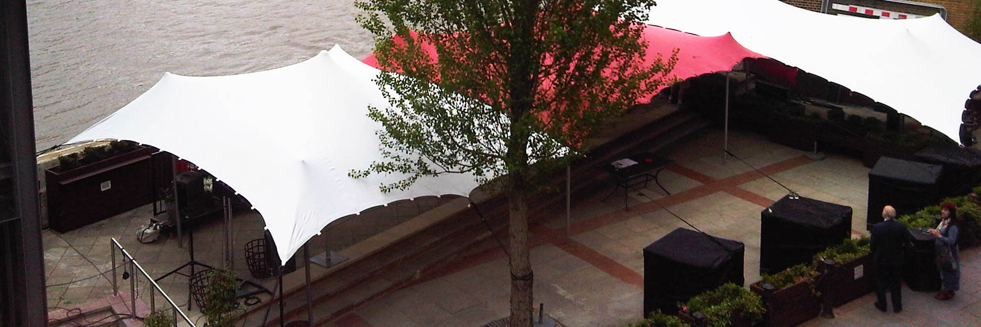 white and red stretch tent along side River thames held down with ballast