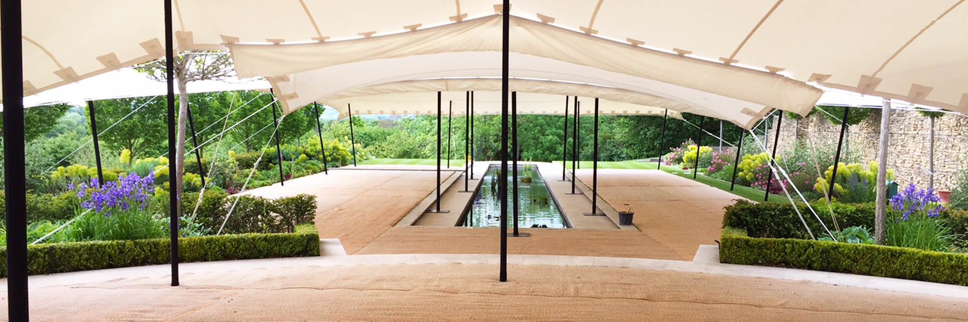 White stretch tent over pond and hedges with matting