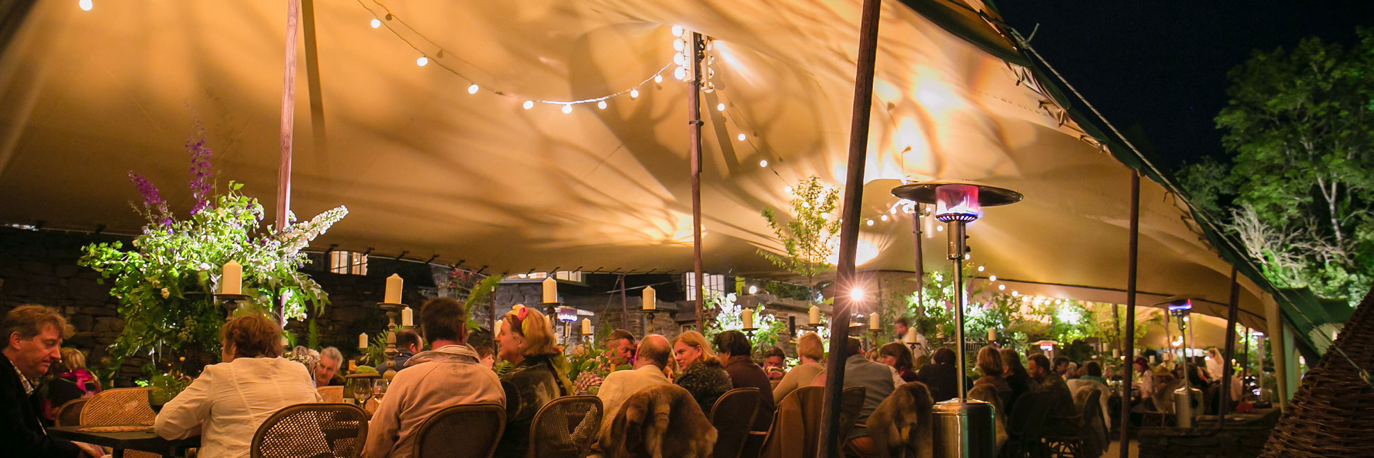 Beige stretch tent, guests, fairy lights, patio heater