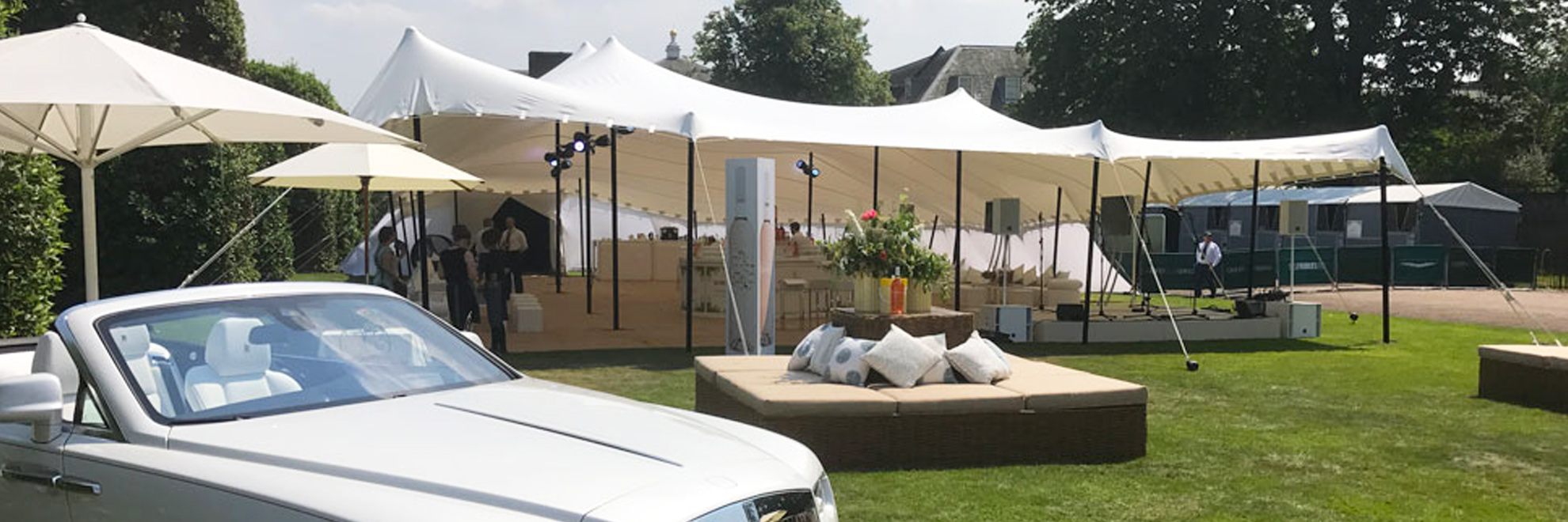 White stretch tent with wicker sofa and bentley in foreground